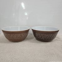 Two vintage Pyrex mixing bowls shown side by side highlighting the brown exterior and white floral pattern.