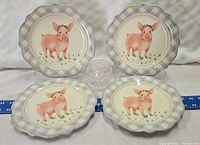 Four ceramic plates displayed with pig illustration and checkered border