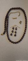 Full set of jewelry items including dark pearl necklace, pearl earrings, small angel pendant, small 14k gold hand pendant, and clasp extender chain.