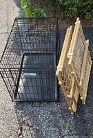 Full view of black metal animal cage and two folded wooden gates lying on pavement outdoors