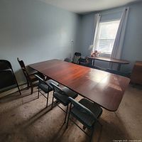 Side and top angled view of large wooden drop leaf dining table set with extension leaves up and surrounded by chairs.