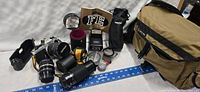 Wide overview of camera body, two zoom lenses, flash head, instruction manual, lens pouches, case and assorted accessories laid on table
