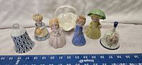 Photo showing a row of porcelain decorative bells and figurines with a white porcelain basket at the center