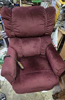 Front view of maroon fabric power lift recliner chair with cushioned backrest and padded armrests. Remote control is visible on the armrest.