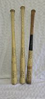 Three vintage Louisville Slugger baseball bats standing upright, showing full length and branding details.