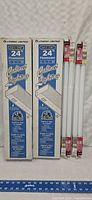 Two boxed Lithonia Lighting 24 inch Quick Start fluorescent under cabinet lights and four new 24 inch T8 fluorescent tubes in packaging.