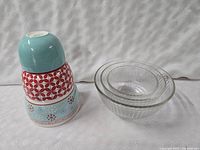Nesting bowls stacked; three ceramic Holiday 09 bowls with colorful patterns and three clear Pyrex glass bowls.