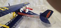 Close-up image of the dark blue die-cast metal biplane showing two white polar bear figures in the cockpit, Coca-Cola branding on the body and tail fin.