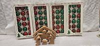 Four boxed sets of red and green Christmas balls arranged vertically in their trays, each set containing 18 ornaments.