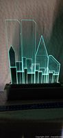 Front view of acrylic New York City skyline art piece illuminated from base, showing Twin Towers and other buildings glowing in light.