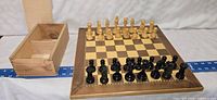 Wooden chessboard with chess pieces set up and finger joint storage box visible