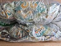 Two Pillow Perfect Pretty Witty Reef Blue reversible chair pads stacked in packaging, showing colorful reef-inspired pattern with blue, green, orange, and beige tones.