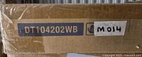 Photo of the product packaging showing the model number DT104202WB and lot identifier M014.