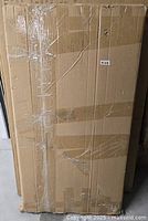 Large sealed cardboard box containing the Richell freestanding pet gate, taped and wrapped for shipping or storage.