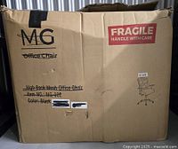 Closed, slightly damaged cardboard box with printed details and label for an MG brand office chair, indicating high back mesh design, item number MG-002, black color. Box includes fragile handling sticker and a small illustrative sketch of an office chair.