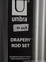 Close-up of Umbra branding on packaging and part of curtain rods visible behind packaging