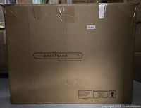 Large sealed cardboard box labeled 'Daya Lane' containing the chair components.