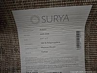 Photo of the label on the Surya rug showing brand, collection, design, size, content, construction, origin and care instructions.