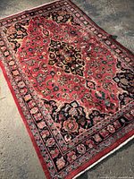 Full view of red floral medallion rug on concrete floor