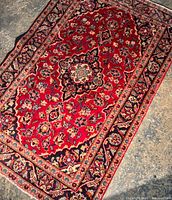 Full overview of the red Kashan rug showing floral design and central medallion with borders.