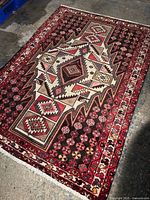 Full view of Persian Saveh rug laid on concrete floor showing geometric central pattern and border designs.
