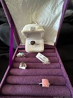 Five sterling silver rings arranged in a purple jewelry organizer, showing various gemstone shapes and bands.