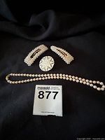 Photo showing the pearl necklace, two decorative hair barrettes, and the snowflake brooch on a black background.