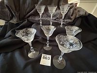 7 Cambridge Portia etched wine glasses with twisted 3121 stems arranged on black fabric, showing front and side angles.