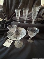 Photo showing seven Cambridge Portia depression era stemware pieces with detailed etched floral patterns, including 3 tall footed glasses, 2 oyster cocktail glasses, and 1 low sherbet glass.