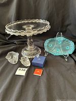 Photo showing all items: crystal cake stand, blue satin glass dish on stand, three clear crystal swans, Swarovski box and booklet