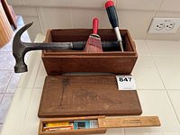 Set of vintage hand tools and brushes inside a wooden box with two additional wooden boxes in front on a white surface.