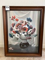 Full view of the original oil painting showing a floral bouquet in a vase on a stand with visible paint texture and muted draped background, framed in wood with wear.