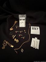 Photo showing full assortment of costume jewelry laid on black fabric including necklaces, earrings, cufflinks and pins.