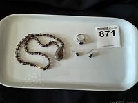 Photo of the full set on a white tray, showing necklace, ring, and earrings arranged with lot number card.