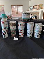 Photo showing all six Swig Life drinkware items arranged on a dark fabric background in a living room setting with windows and fireplace in the background.