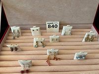 Front angled view of ten pairs of earrings displayed inside the beige interior of the red jewelry box