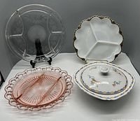 Photo of four vintage divided dishes and lidded vegetable dish on white surface, display stand used for clear dish