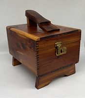 Front angled view showing wood grain, finger joints, brass latch, and wooden handle on top.