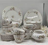 Full set of Johnson Brothers Snowhite Regency Ironstone dishes showing dinner plates stacked at the back, teacups and bowls in front, creamer and sugar bowl on the side.