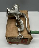 Side view of Kenrick No. 5 meat grinder mounted on original box showing green handle and clamp mechanism