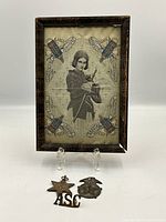 Framed tapestry on easel with medals at base