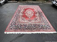Full view of rug laid flat on pavement showing entire rectangular shape and fringe