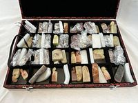 Open decorative case showing foam-lined compartments filled with soapstone seals.