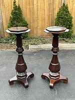 Front view of both walnut pedestals outdoors on pavement with fence backdrop