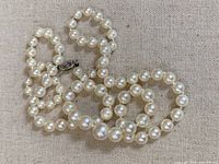 Strand of off-white round pearls laid on fabric showing entire necklace