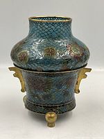 Front view of the blue plique-a-jour floral vase showing round body and gold-tone handles and rim.