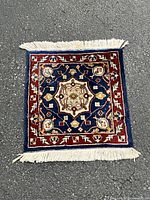 Full view of the small decorative prayer rug showing its central medallion and border design with fringe on one edge.