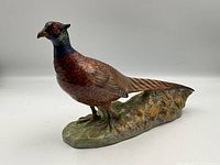 Side view of Royal Doulton cock pheasant figurine showing full length and naturalistic base.