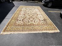 Full view of rug laid flat on pavement with vehicles in background