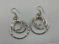 Pair of sterling silver nested hammered hoop pierced earrings on white background